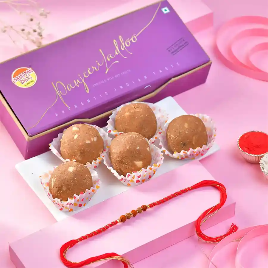 Heartfelt Rakhi adorned with gourmet sweets including Panjeeri Laddoo and traditional Roli Chawal Card for Raksha Bandhan.