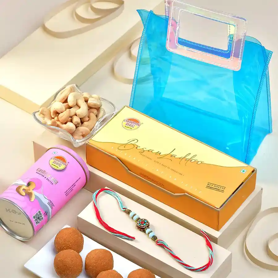Regal Rakhi Indulgence Gift Set with Royal Beads Rakhi, Besan Laddoos, and Cashews in a transparent gift bag.