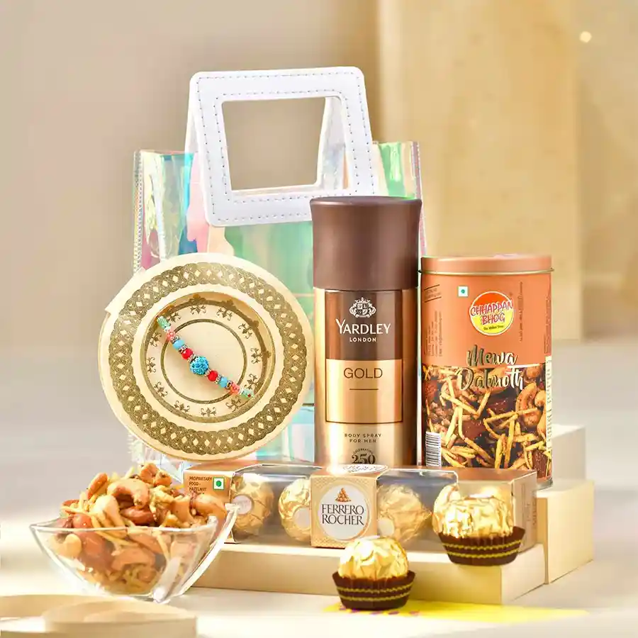 Memorable Rakhi Gift Ensemble featuring a beaded rakhi, snacks, body spray, chocolates, and decorative elements in a transparent gift bag.