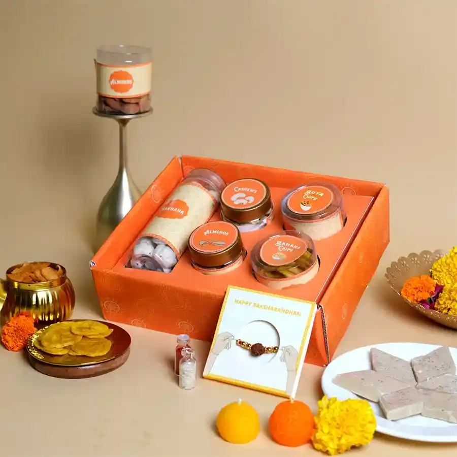 Wholesome Crunch & Rakhi Delight Pack featuring Rudraksha Rakhi and assorted snacks in a festive tray.