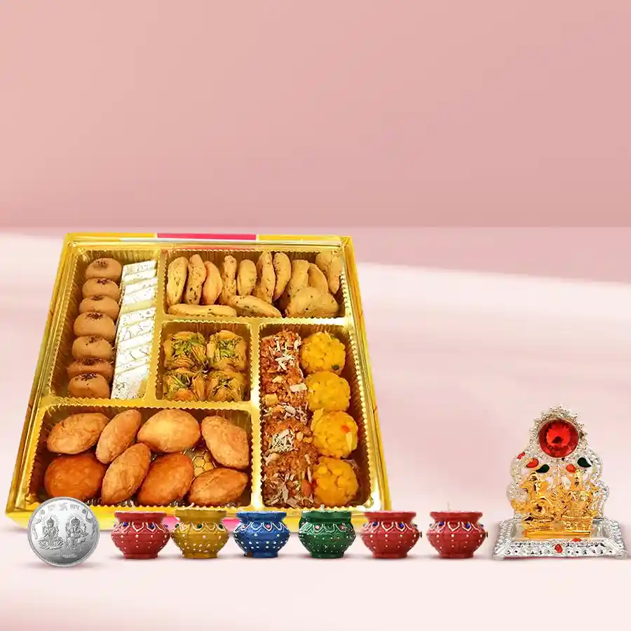 Sweets and snacks platter from Bhikaram for Diwali featuring Mathri, Masala Kachori, Mini Samosa, Kaju Katli, Kesaria Peda, and Besan Ladoo, with Laxmi Ganesh Mandap coin and six diyas.