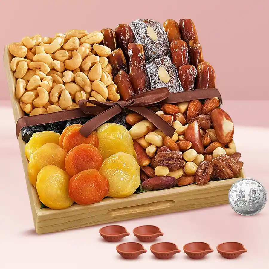 Premium Diwali snacks dry fruits platter featuring dried apricots, prunes, dates, roasted almonds, and cashews in a wooden tray, accompanied by six designer diyas and a silver-plated Ganesh Lakshmi coin.
