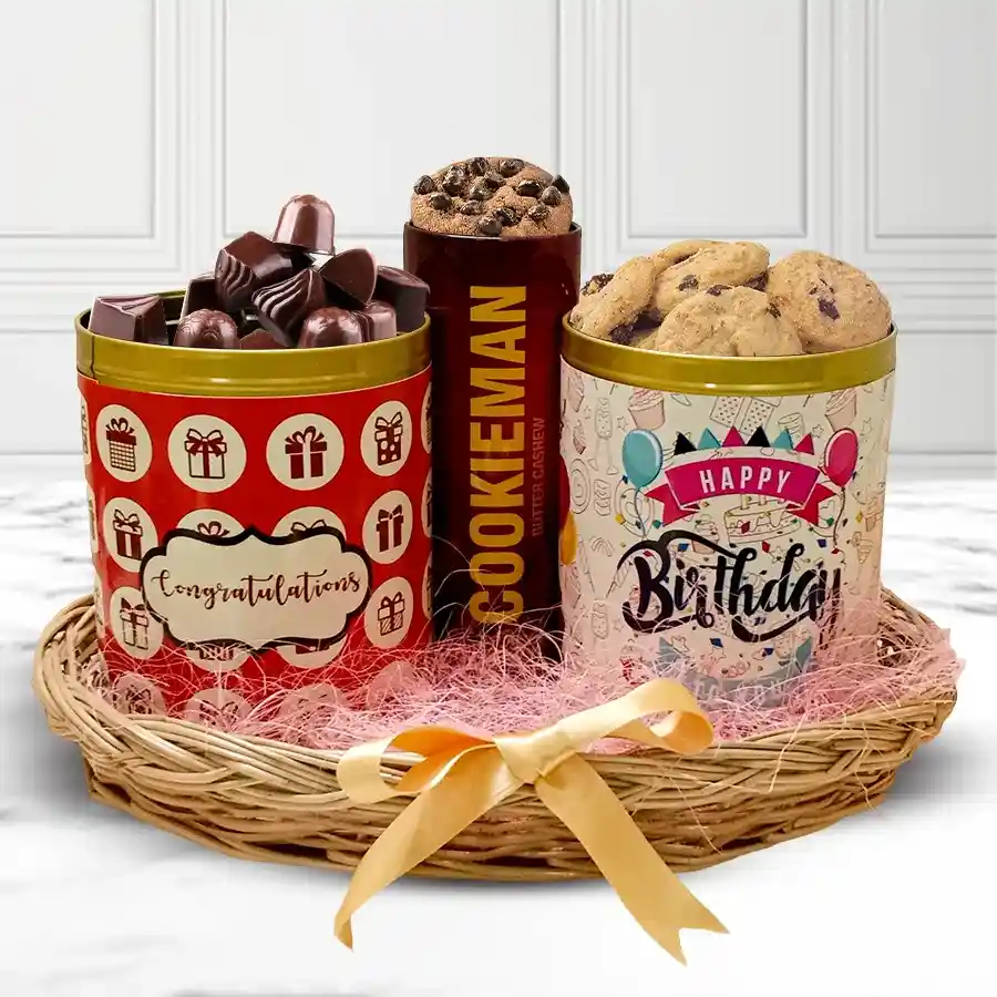 A charming cane basket filled with a 200g tin of crunchy handmade chocolates, a 200g tin of assorted handmade candies and jellies, and a 100g tin of Cookie Mans Chocochip Cookies.