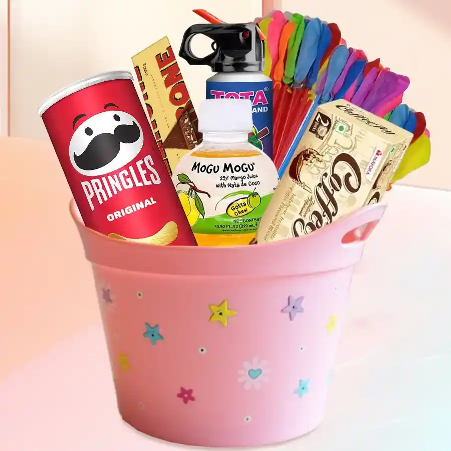 Ravishing Holi Balti Hamper filled with treats including Coffee Joy Cookies, Mogo Fruit Juice, Pringles Chips, Toblerone chocolates, Thunder Strong Colour Spray, water balloons, and filling straws, arranged in a stylish tub.
