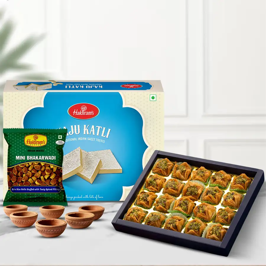 Joyful Gift box featuring Pyramid Baklawa, Haldiram Kaju Katli, Haldiram Bhakarwadi, and Kuber Mud Diyas for Diwali celebration.