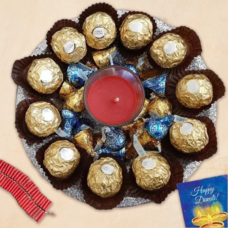 Superb Diwali Chocolates Thali featuring 12 Ferrero Rocher chocolates, a pack of Hershey’s Kisses in various flavors, an Iris Shot Glass Aroma Candle, all arranged in a silver glitter steel thali.