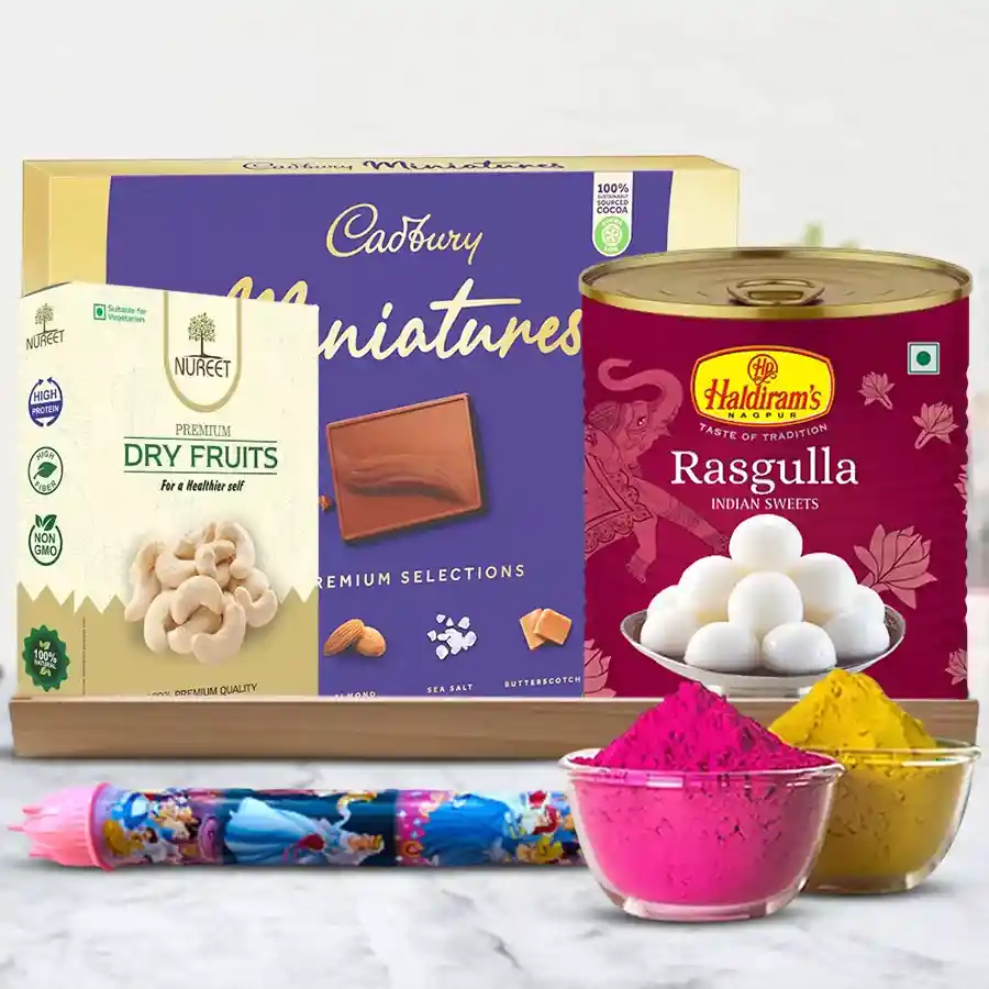 A vibrant gift basket with Haldiram Rasgulla tin, Cadbury Dairy Milk Mini chocolates, crunchy cashews, a pichkari, colorful herbal gulal, all arranged in a wooden tray for Holi celebrations.