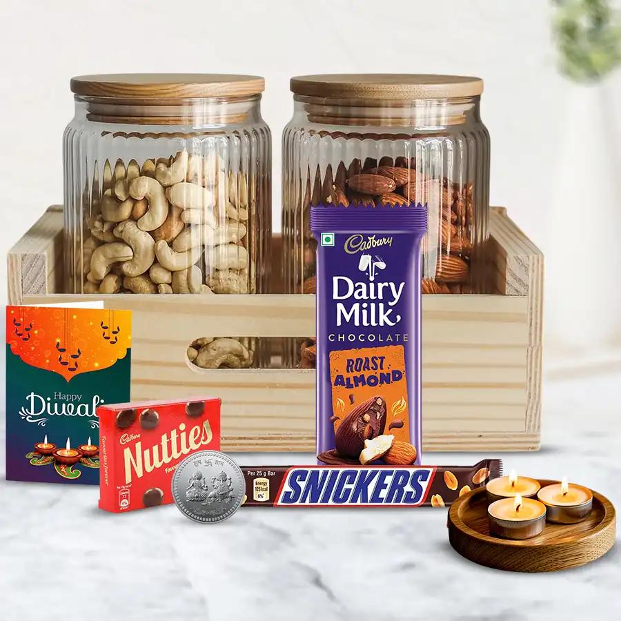 Tasty Affair Nuts n Chocolates Hamper featuring a wooden tray with glass jars of cashews and almonds, assorted chocolates, tea light candles, and a silver-plated Ganesh Laxmi coin.