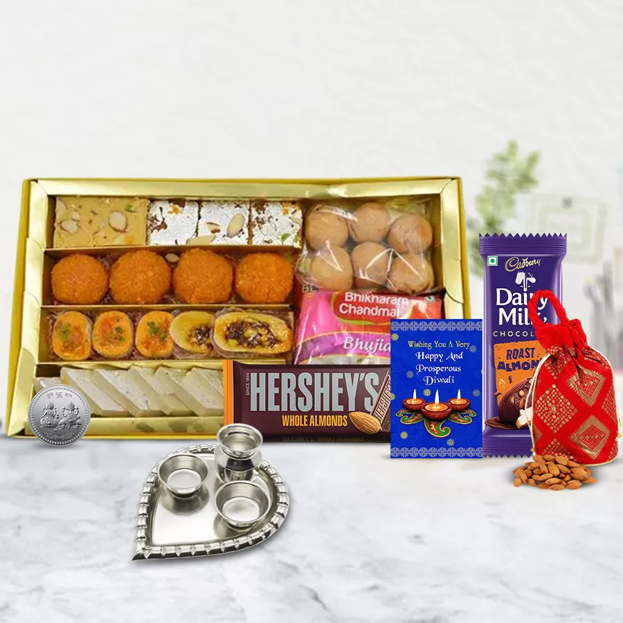 Premium Sweets and Chocolates Gift Hamper with traditional Indian sweets, chocolate bars, decorative Ganesh and Laxmi coins, almond potli, and a paan-shaped pooja thali, accompanied by a Diwali card.