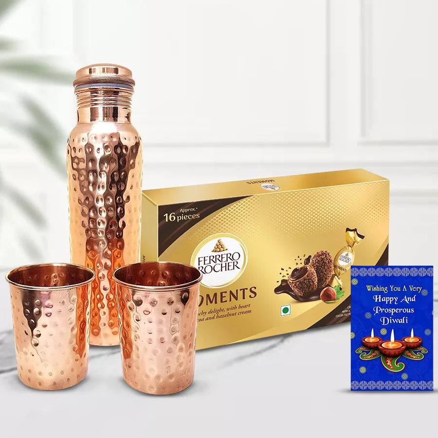 Copper bottle, two elegant glasses, and a box of Ferrero Rocher chocolates with a Diwali wishing card arranged together as a gift set.