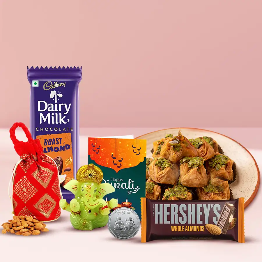 Mouth-melting Pyramid Baklava with chocolate bars, silver-plated Ganesh Laxmi coin, glowing Ganesh idol, crunchy almond potli, and a Diwali card arranged for celebration.
