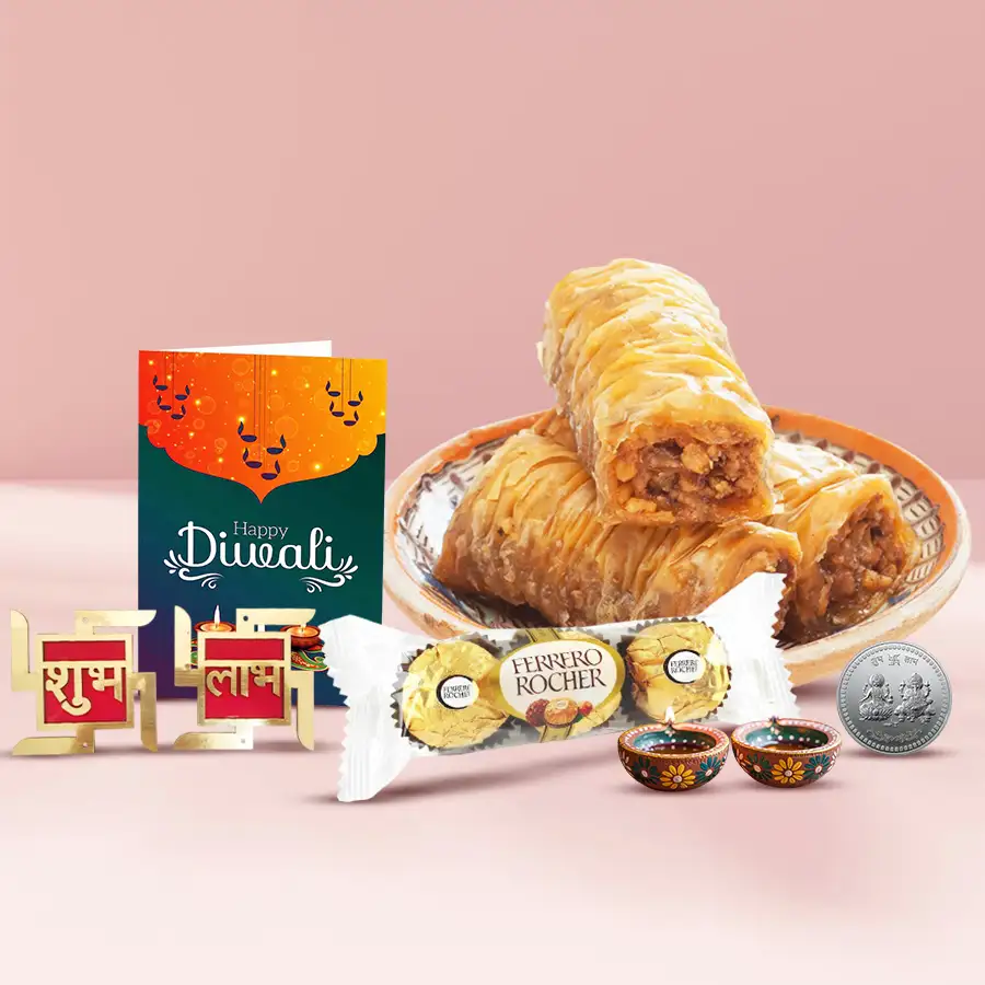 Roll Baklava Moments and Feisty Ferrero gift box featuring 250g of Roll Baklava, three Ferrero Rocher chocolates, a fancy diya, a silver-plated Ganesh-Laxmi coin, Shubh Labh wall stickers, and a free Diwali card.