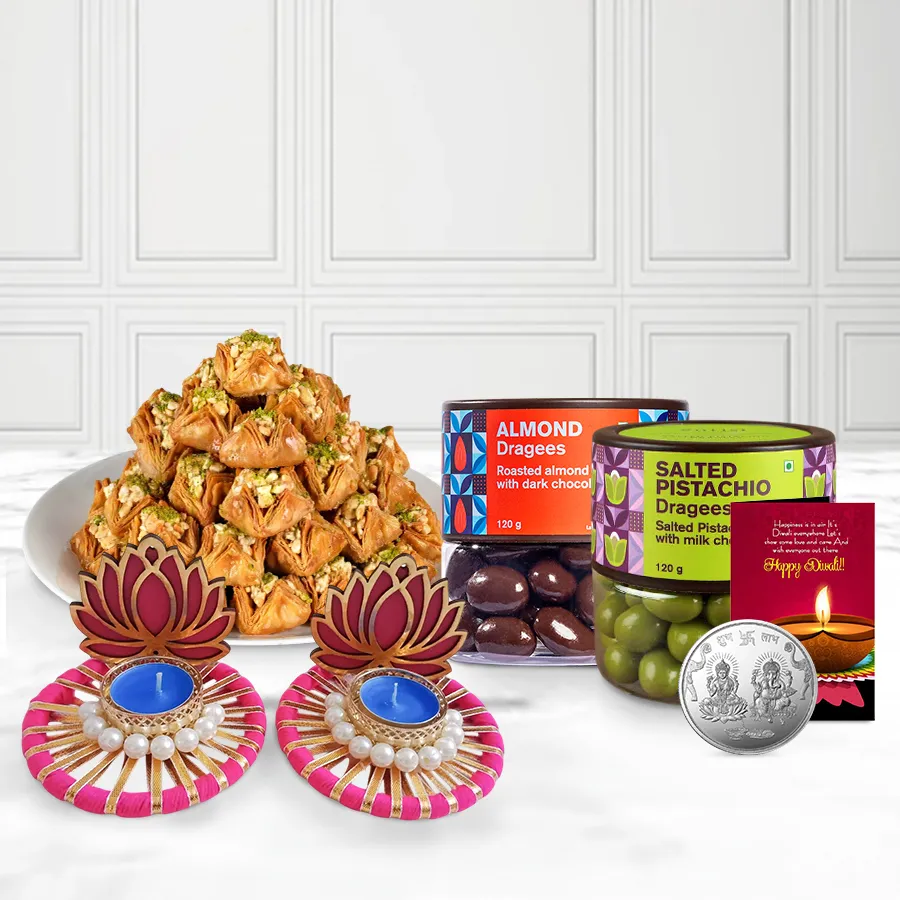 A festive Diwali gift basket containing almond dragees, pistachio dragees, pyramid baklava, two lotus diyas, a Ganesh Lakshmi coin, and a Diwali card.