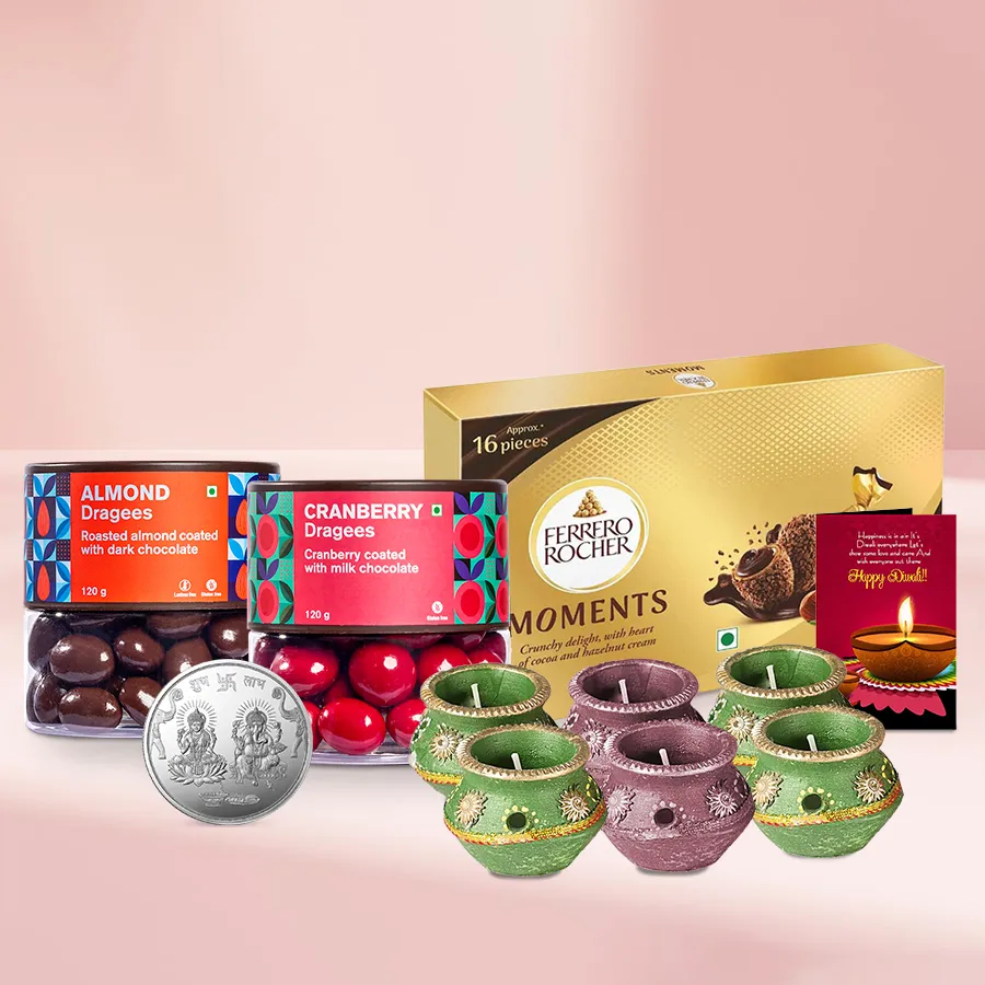 Mixed Bag Dragee N Ferrero Magic festive basket with almond and cranberry dragees, Ferrero Rocher Moments, wax diyas, silver-plated coin, and Diwali card.