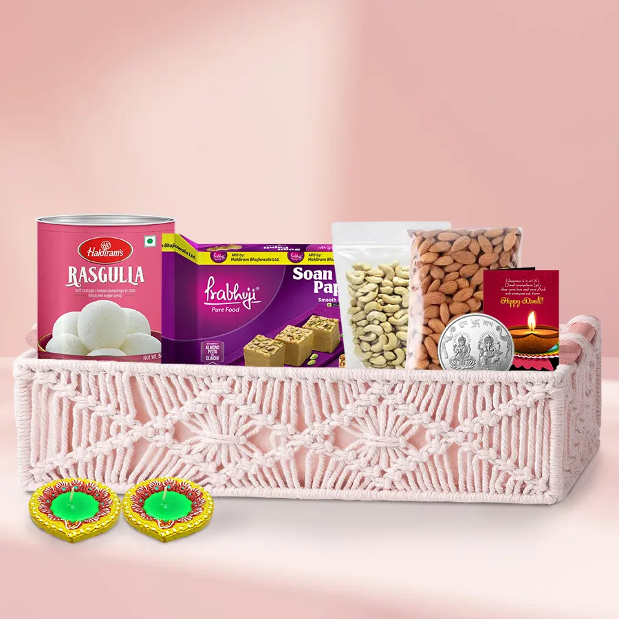 Diwali hamper featuring sweets, dry fruits, Ganesh-Laxmi coin, and designer diyas in a gift basket