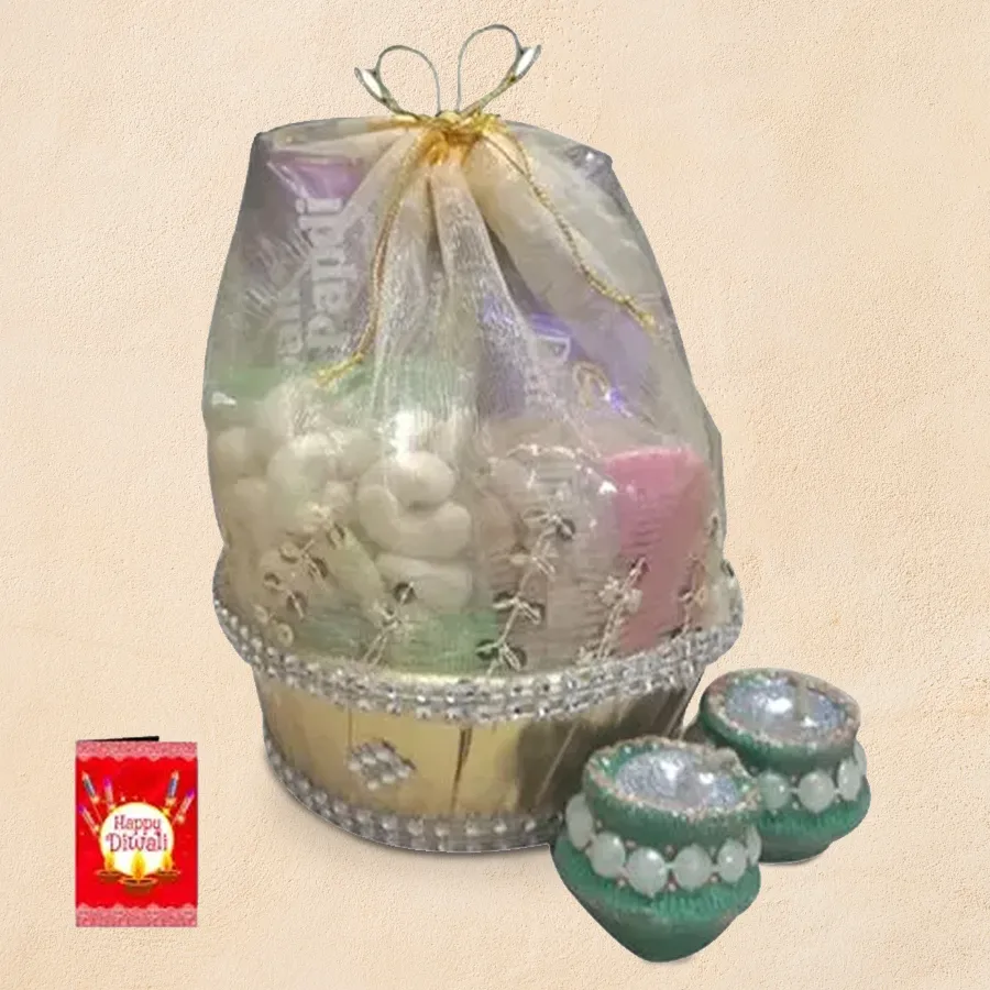 Affordable Diwali gift hamper featuring assorted dry fruits, Bhikaram Soan Papdi, a Snickers bar, decorated wax diyas, and a greetings card in a net basket.