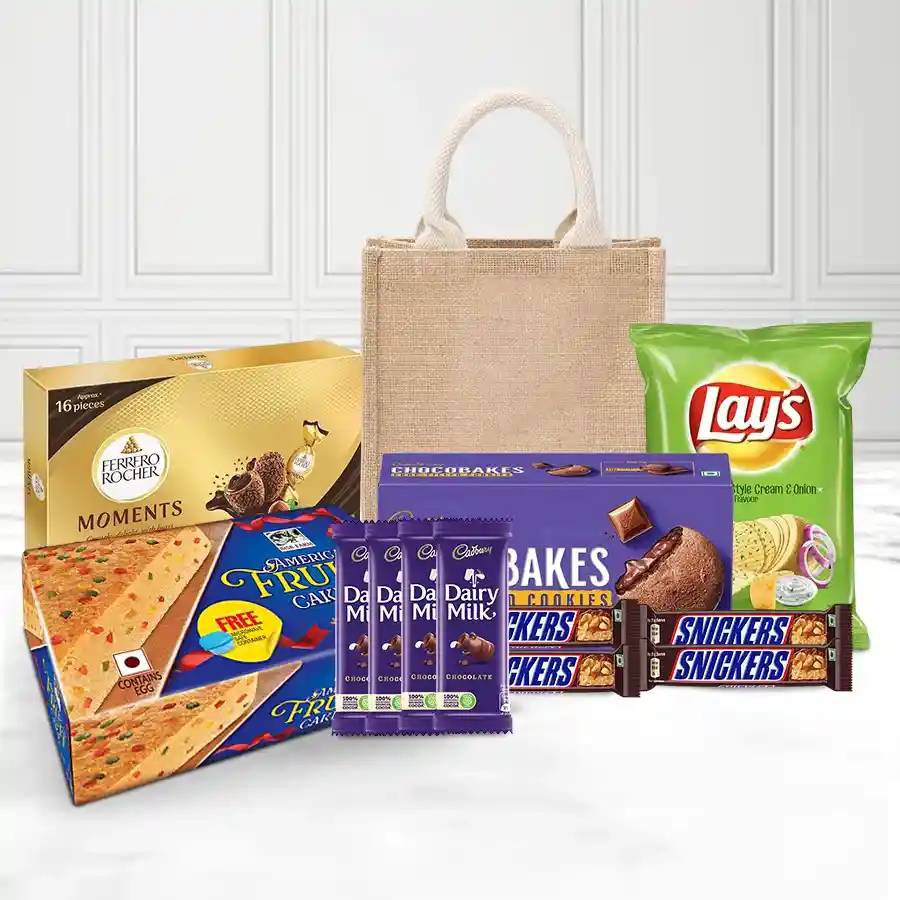 Christmas gift hamper filled with assorted treats including fruit cake, Cadbury bars, Snickers, Chocobakes, potato chips, and Ferrero Rocher pieces in a reusable jute bag.