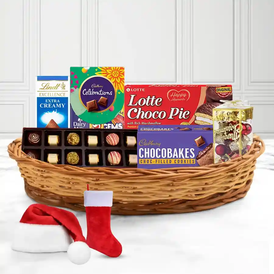 Marvelous Chocolate and Christmas Decor Gift Basket featuring Cadbury Celebration Minis, Lindt Excellence bars, handmade chocolates, festive decorations, Christmas caps, stockings, and a reusable cane basket.