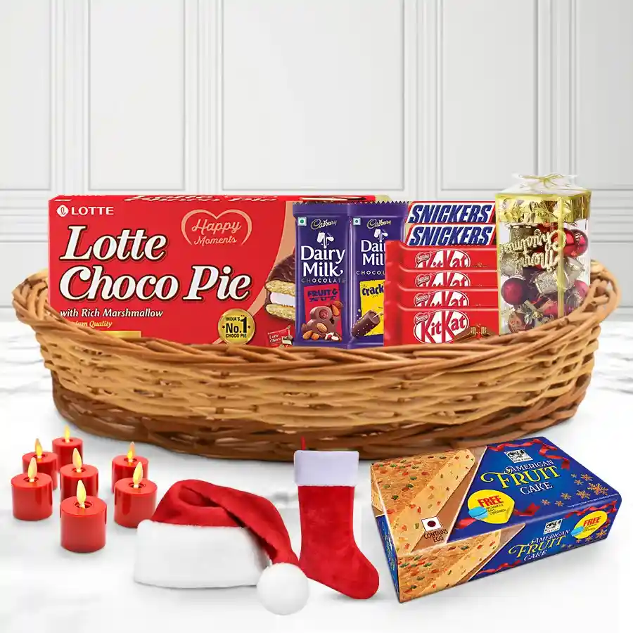 Luxurious Christmas Treat Gift Basket filled with festive goodies, including American Fruit Cake, Cadbury chocolates, Lotte Chocopie, KitKats, Snickers, Christmas decorations, tealight candles, caps, and stockings in a reusable cane basket.