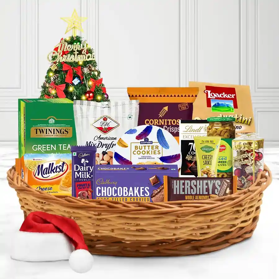 A beautifully arranged festive snack hamper filled with Twinings tea, Cadbury chocolates, mixed nuts, crispy cookies, and savory treats, adorned with holiday decorations in a reusable gift basket.