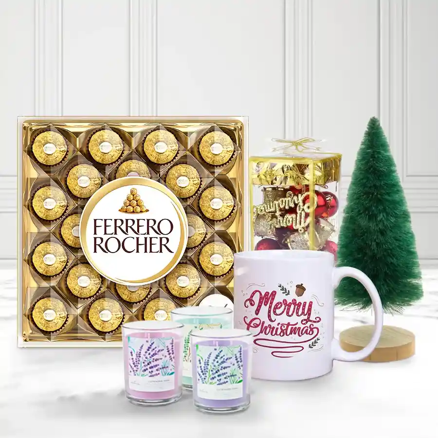 Sumptuous Ferrero Rocher chocolate box, festive "Merry Christmas" mug, three aromatic scented candles, and a decorative Christmas tree with ornaments arranged for a cozy holiday setting.