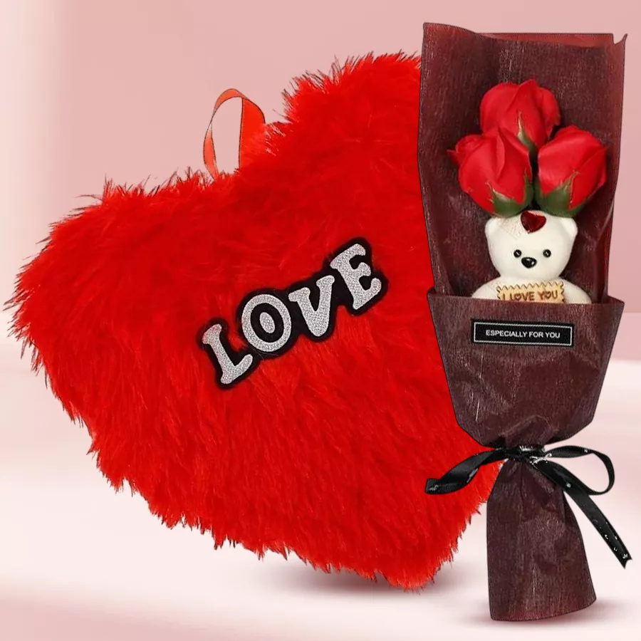 Gorgeous artificial red roses with a teddy bear and a red heart-shaped cushion arranged in a bouquet.