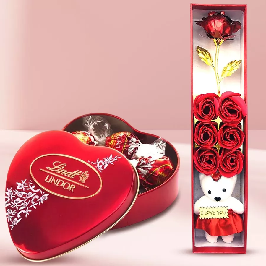 Valentine's Day surprise box featuring a red artificial rose, a teddy bear, a luxurious scented perfume, and a Lindt Lindor chocolate box.