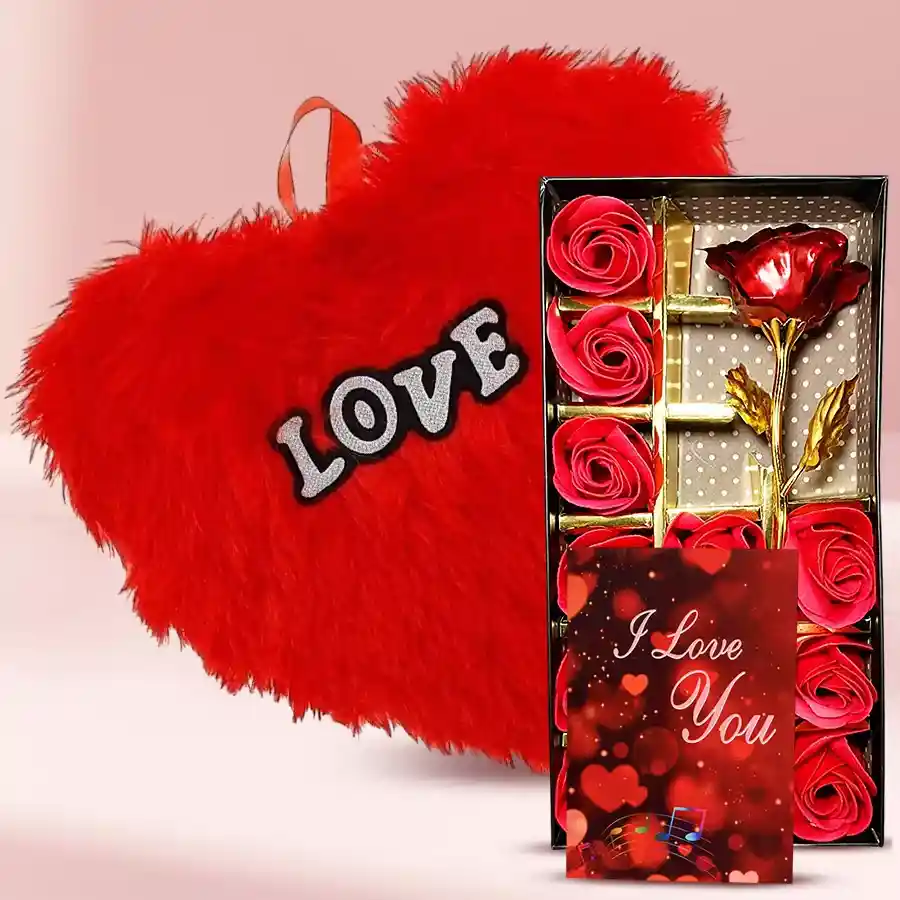Exclusive pair of artificial red roses in a decorative box, a heart-shaped red cushion, and a "I Love You" card arranged together for Valentine's Day gift.