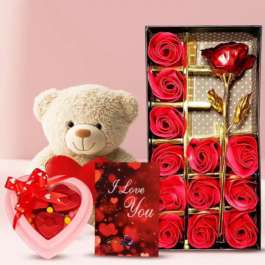 Cream-colored teddy bear with a heart detail, artificial red rose in a flower box, handmade heart-shaped chocolates, and a "I Love You" card arranged together.