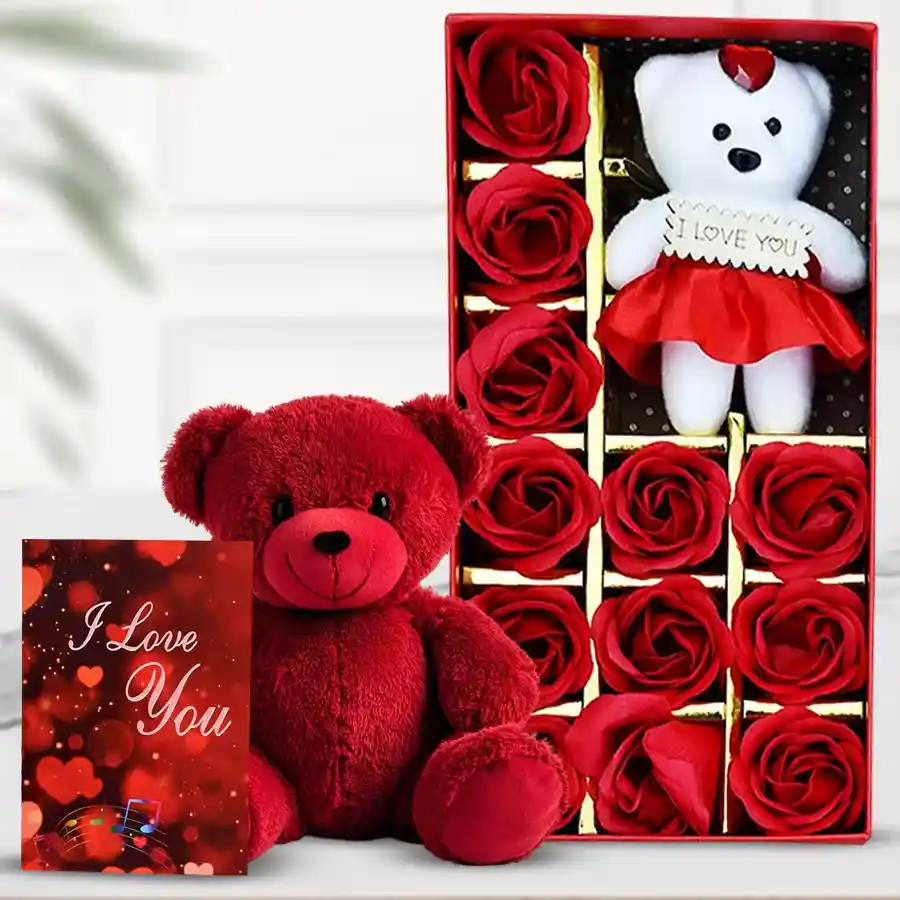 Delightful red teddy bear surrounded by artificial roses in a decorative box with a "I Love You" card