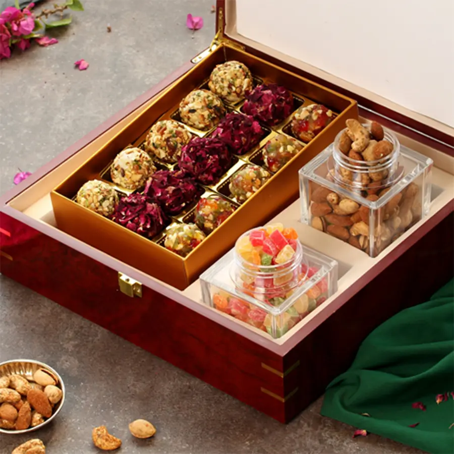 Yummy Holi Delight Gift Hamper featuring rose petal laddoo, very berry laddoo, almond gujiya dryfruit laddoo, berry mixture, mixed nuts, and a Holi greetings card in a lacquer wooden box