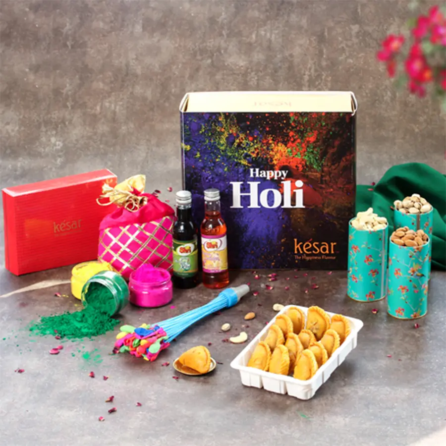 Scrumptious Sweet N Nuts Treat box with Kesar Gujiya, premium nuts, herbal colors, water balloon, sharbat bottles, and a greetings card in a green handbag box.