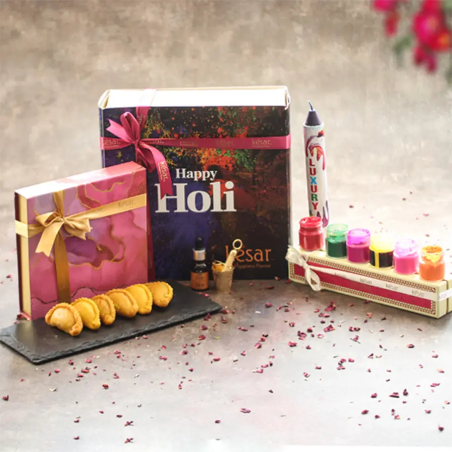 Delectable Gujiya and Essential Oil Holi Assortment Gift Set with organic colors, pichkari, color bomb, and greeting card in a colorful box