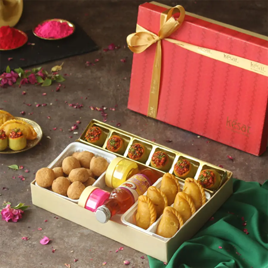 Irresistible Sweet N Savory Holi Gift Hamper featuring Paan Badam Ladoos, Kesar Gujiyas, Mini Kachoris, Mini Thandai bottle, colorful Gulal bottles, and a Holi greetings card in a charming gift box.