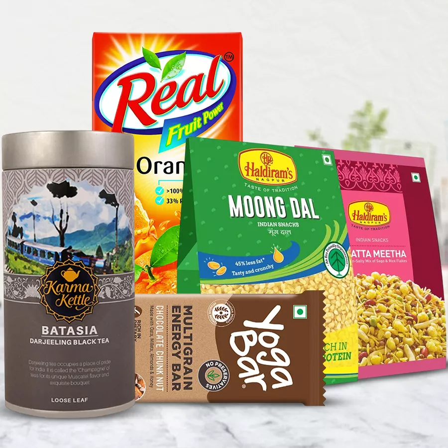 Remarkable hamper featuring Batasia Tea, Haldiram savories, and juice, including Karma Kettle Batasia Tea, Yoga Bars, Moong Dal, and Khatta Meetha Mixture.