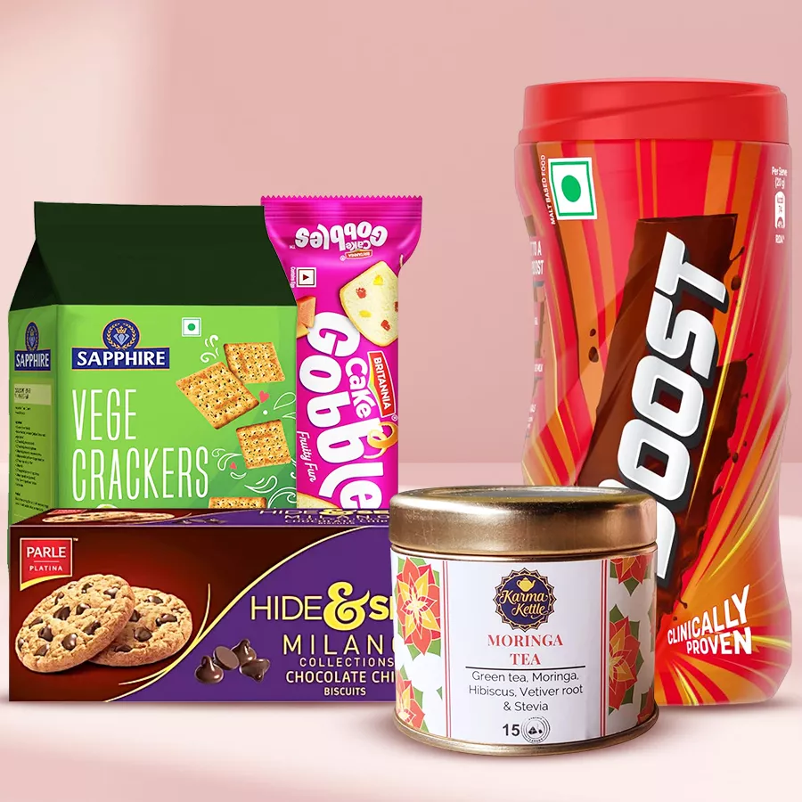 A beautifully arranged hamper featuring Aromatic Moringa Tea, Britannia Cake, Sapphire Veg Crackers, Milano Cookies, and Boost Health Drink, all presented in an aesthetically pleasing way.