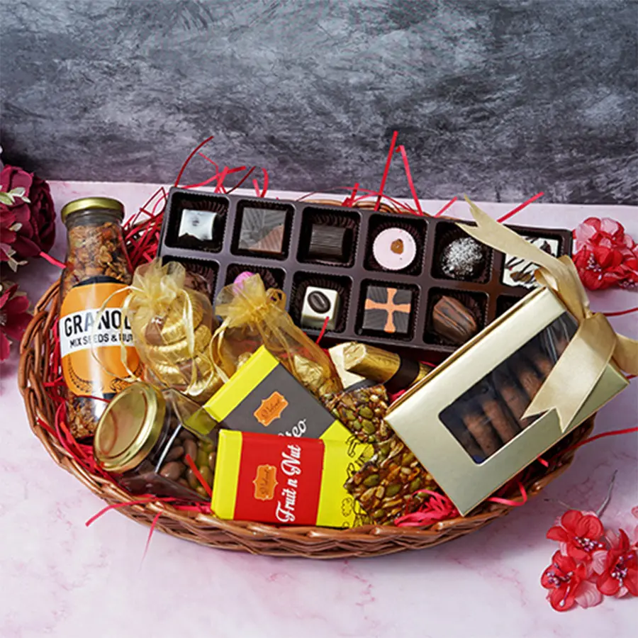 A beautifully arranged Mother's Day basket filled with assorted chocolates, granola, chocolate-covered raisins, almond florentines, fruit and nut chocolate bars, seed squares, and cookies.