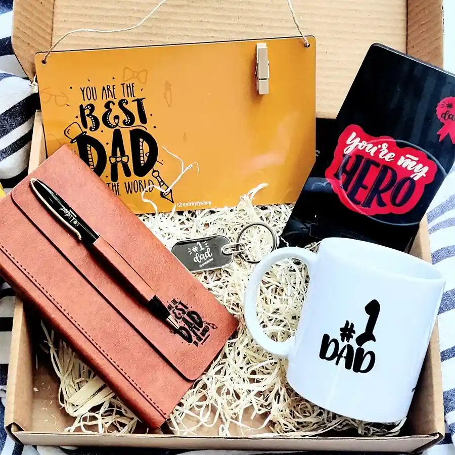 Marvelous Gift Hamper for Workaholic Dad featuring a pocket diary, stylish metal pen, cozy coffee mug, classy keychain, Hero Dad mobile stand, and a charming wall hanging with picture clip.