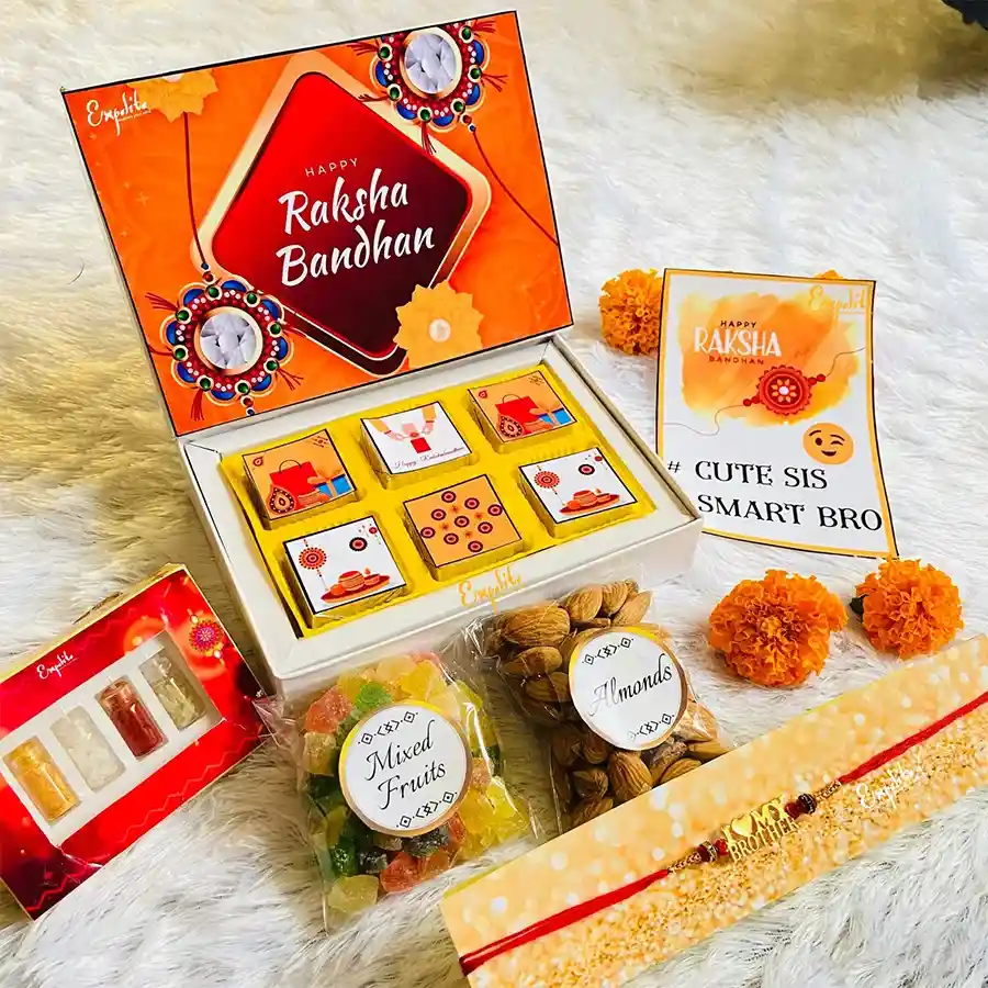 Outstanding Rakhi hamper featuring a vibrant red mauli rakhi, six assorted chocolates, 30g of premium almonds, a mix of dried fruits, and complimentary Roli Tikka, Chandan, Chawal, Mishri, and a Rakhi greeting card, all beautifully packaged with Rakhi-themed designs.