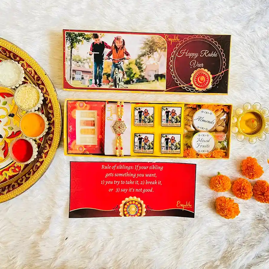 Fabulous Rakhi with Choco N Nuts Personalized Hamper featuring a red mauli rakhi with colorful beads, assorted chocolates, almonds, mixed fruits, Roli Tikka, Chandan, Chawal, Mishri, and a greeting card.