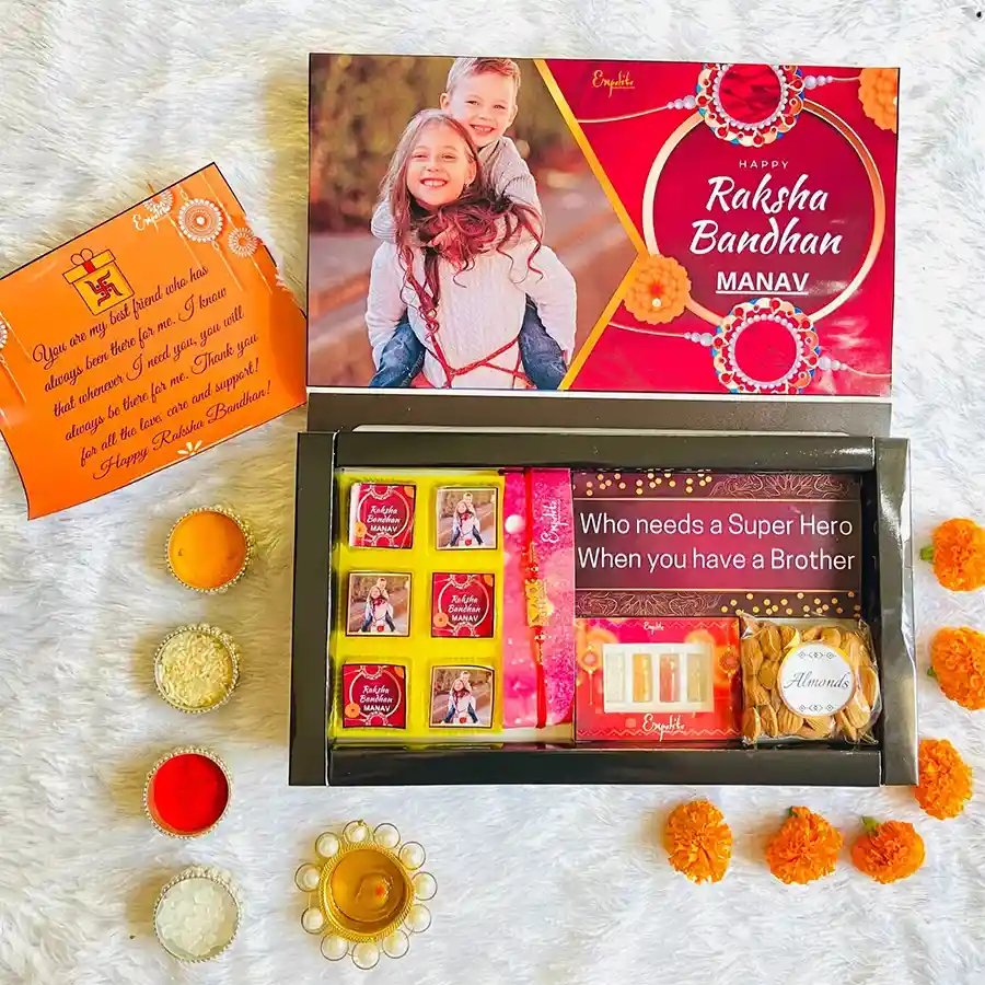Customized Rakhi gift hamper including premium rakhi, assorted chocolates, almonds, chocolate bar, traditional Roli Tikka set, and greeting card.