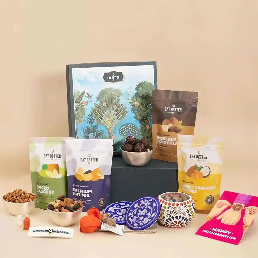 Brother Rakhi Amazing Medley Hamper featuring Evil Eye Rakhi, vegan sweet mixes, high-protein treats, Moroccan candle, blue pottery coasters, seed bomb, Roli, Tilak, Chawal, and greeting card.