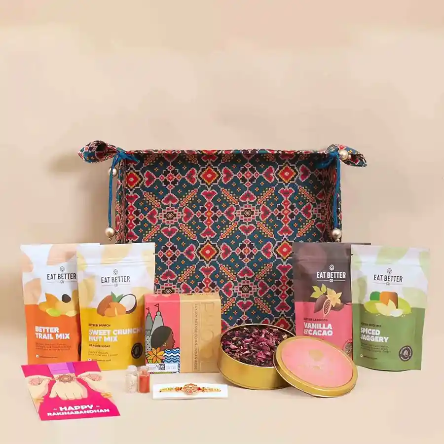 Patola Design Bhaiya Rakhi Mouthfuls Pack including handcrafted Rakhi, Roli, Tilak, Chawal, greeting card, vanilla and chocolate dry-fruit laddoos, nut mixes, jaggery seed mixes, rose tea, incense cones, and reusable Patola art fabric tray