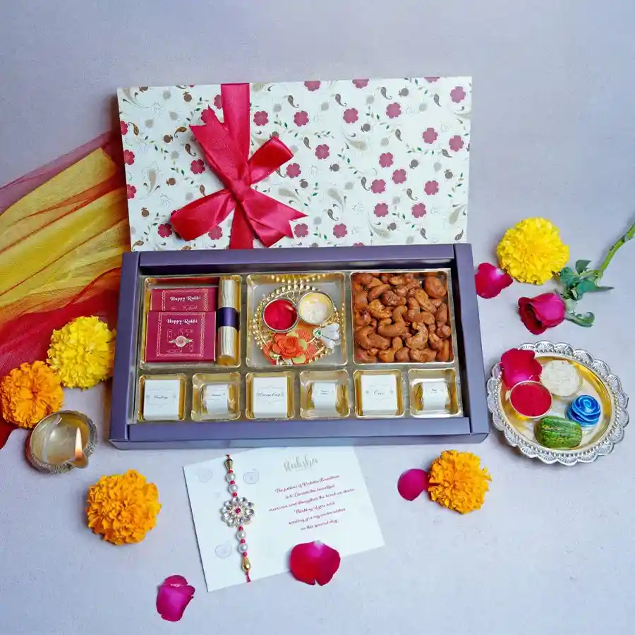 Winsome Box of Rakhi N Chocolates featuring a milk chocolate bar, orange crisp log, Cajun cashews, assorted chocolates, a Kumkum thali, designer rakhi, and a greeting card.