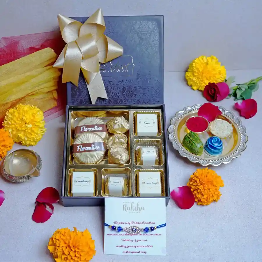 Festive Confections hamper with assorted chocolates, Chocolate Almond Florentines, Chocolate Almond Rocks, a designer Rakhi, and a greeting card in a brown box.