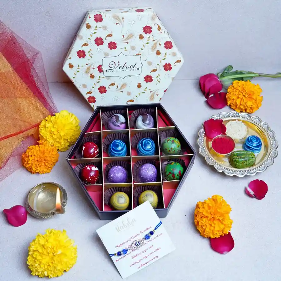 Hexagonal Bon Bon Box with 12 assorted bon bons and a designer rakhi placed beside a greeting card, featuring floral design and vibrant colors.