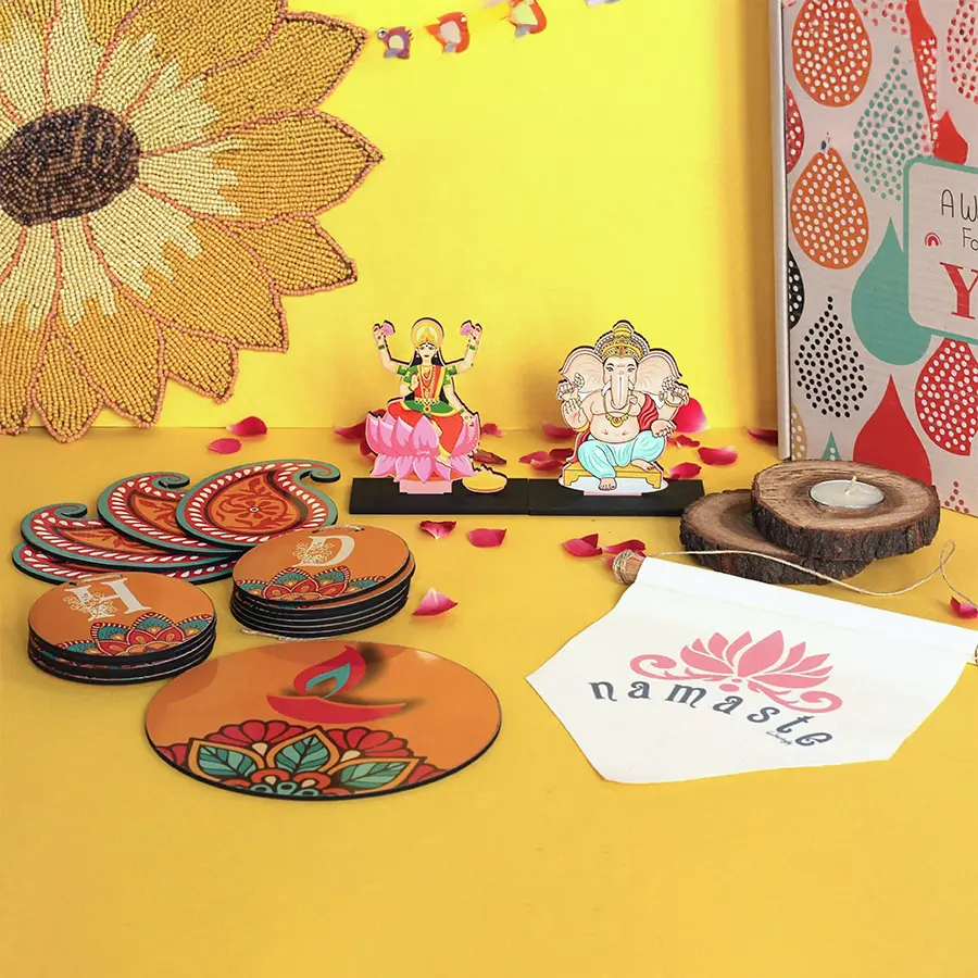 Divine Diwali Delight Box featuring colorful Ganesh and Laxmi idols, festive bunting, Namaste canvas, natural wooden log candles, and rangoli-inspired diyas.