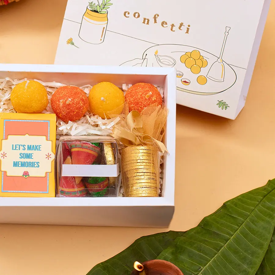 Festive Flames Ladoo Candle Collection featuring a golden box with ladoo candles, golden coin chocolates, and playing cards, designed for Diwali celebrations.