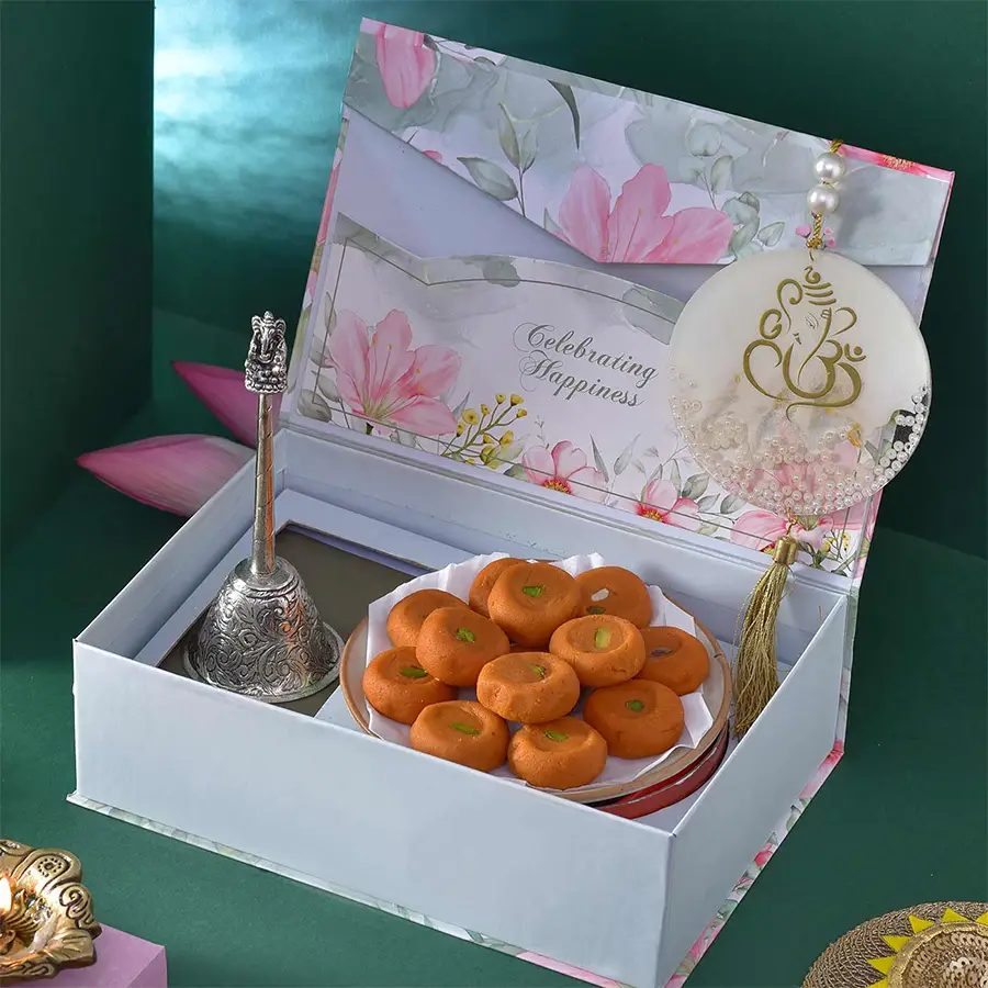 Divine Diwali Box featuring a brass bell, Kesar Peda sweets, a high-gloss resin Ganesha car hanger, and decorative packaging