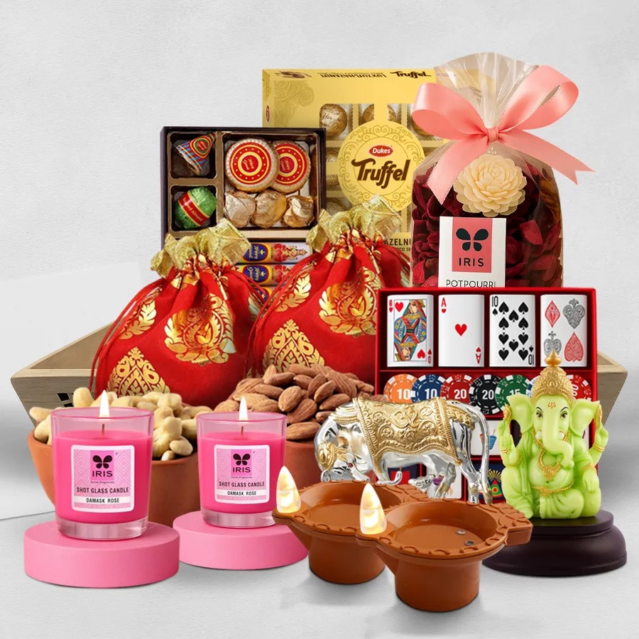 A beautifully arranged wooden tray filled with cashews, almonds, Dukes Truffle chocolates, a Silver Kamdhenu idol, glowing Ganesha and water-led diyas, Iris potpourri, scented candles, and themed chocolates, celebrating the spirit of Diwali.